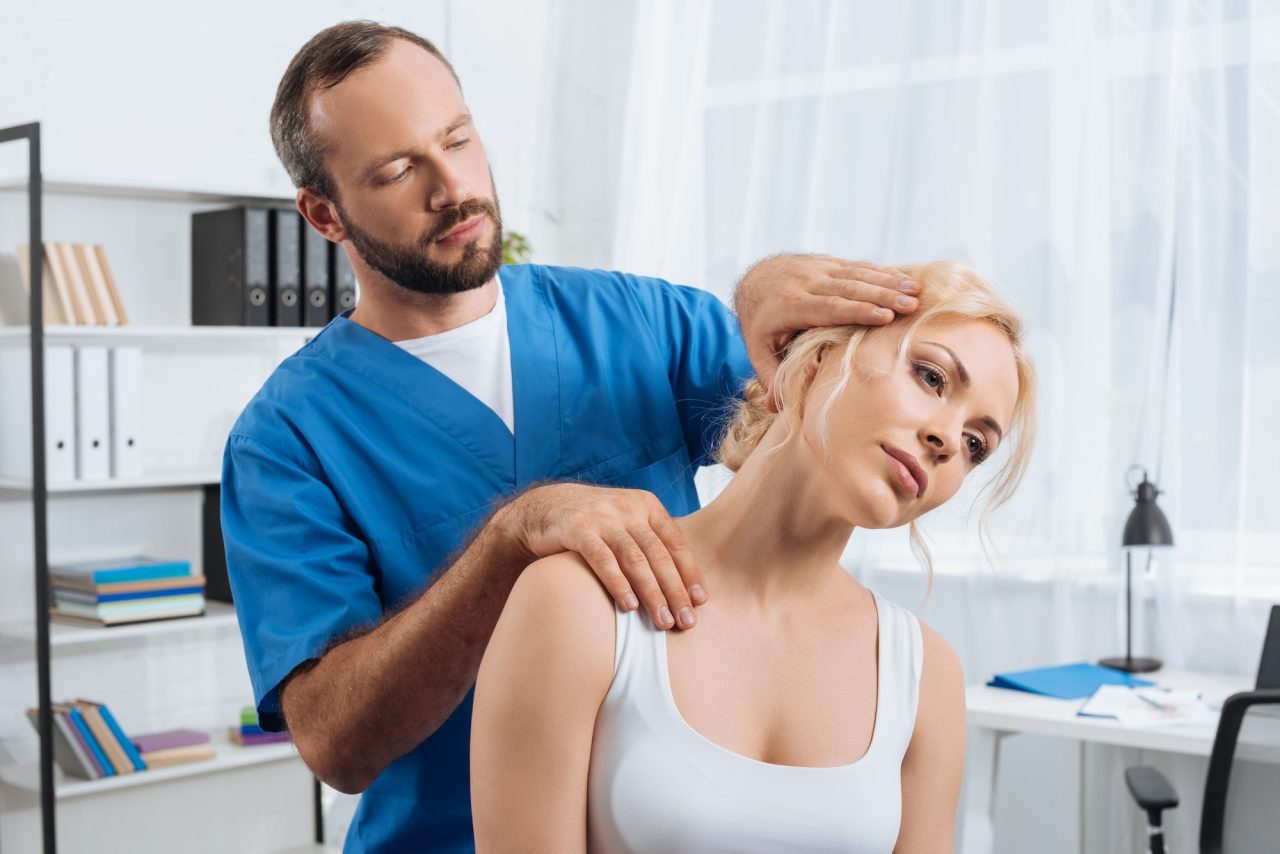 portrait of chiropractor stretching neck of woman during appointment in hospital 1